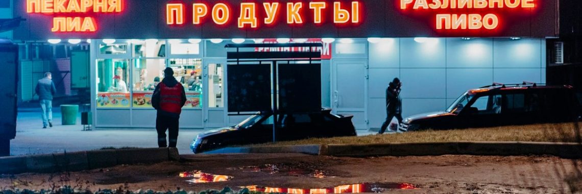 man in black jacket and black pants standing near red and white UNKs store during